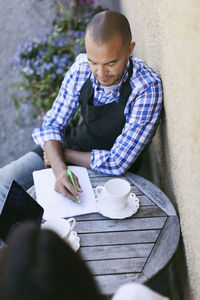 High angle view of owner discussing with coworker at table outside cafe