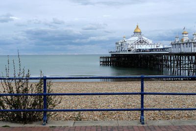 Eastbourne pier and empty beach on a cloudy day with railings in the foreground