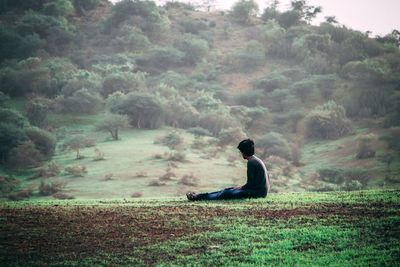 Side view of man sitting on land