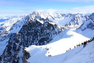 Scenic view of snow covered mountains against cloudy sky