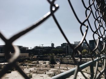 Close-up of cityscape seen through chainlink fence