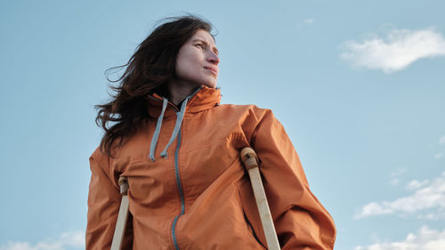 A woman on crutches walks along the shore of the lake.