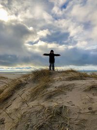 Rear view of man standing on beach against sky