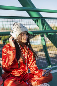 Young woman looking away while sitting on railing