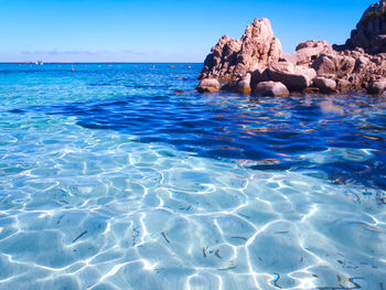 Rocks in sea against blue sky