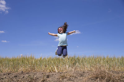 Woman standing on field against clear blue sky