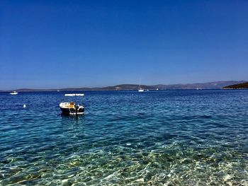 Sailboat sailing in sea against clear blue sky