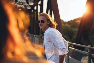 Young woman wearing sunglasses standing outdoors during sunset