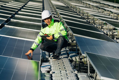 Young asian engineer on background field of photovoltaic solar panels solar cells
