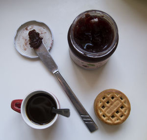 High angle view of coffee with jam and cookie on table