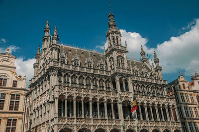 Richly decorated facade in gothic style of brussels city museum and belgian flag.