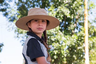 Portrait of girl wearing hat against trees