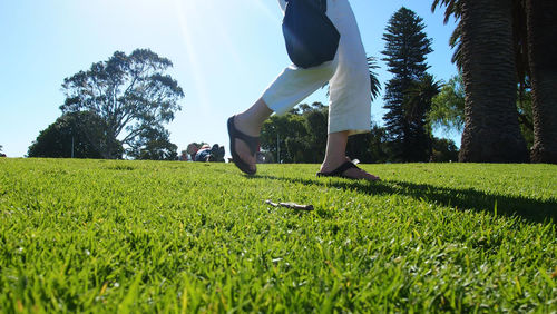 Low section of woman standing on golf course against clear sky