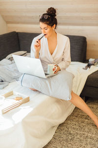Young woman sitting on sofa at home
