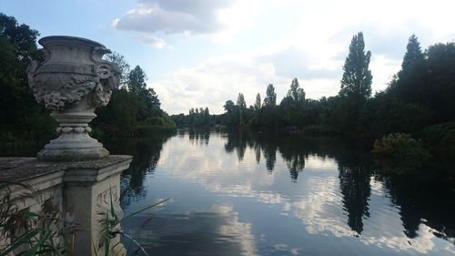 Reflection of trees in lake against cloudy sky