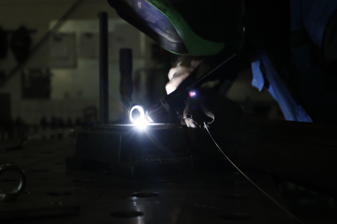 LOW SECTION OF MAN WORKING ON ILLUMINATED METAL