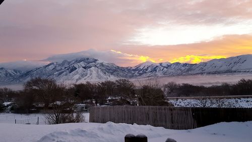 Scenic view of snowcapped mountains against cloudy sky during sunset