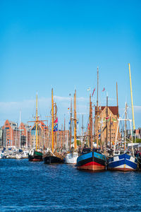 Sailboats in harbor against clear blue sky