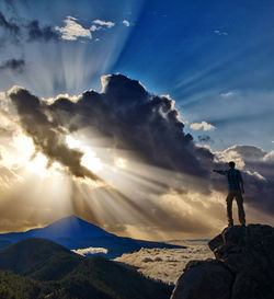 Man standing on rock against sky