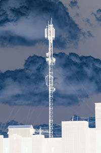 Low angle view of communications tower and buildings against sky