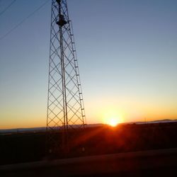 Low angle view of silhouette electricity pylon against sky during sunset