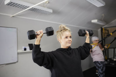 Blond woman exercising with dumbbells at health club