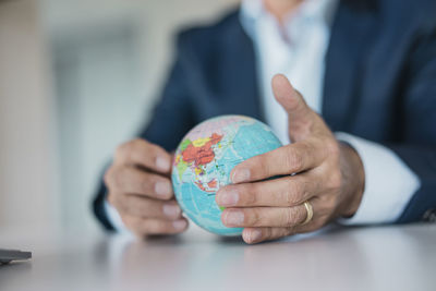 Close-up of hands of businessman holding globe