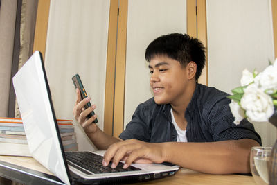 Young man using mobile phone while sitting on table