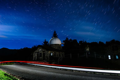 Light trails on road against sky at night