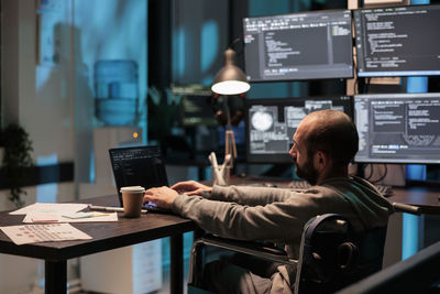 Rear view of man using digital tablet in office