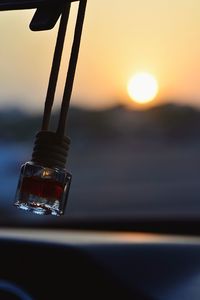 Close-up of lighting equipment hanging against sky during sunset