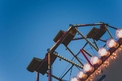 Low angle view of rollercoaster against clear blue sky