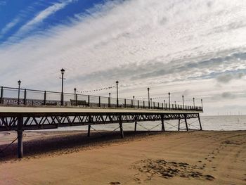 Pier on beach against sky