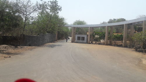 Empty road amidst trees and buildings against sky