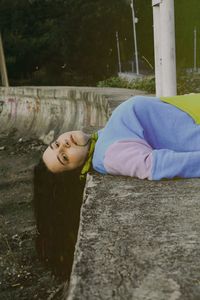 Low section of woman sitting on retaining wall