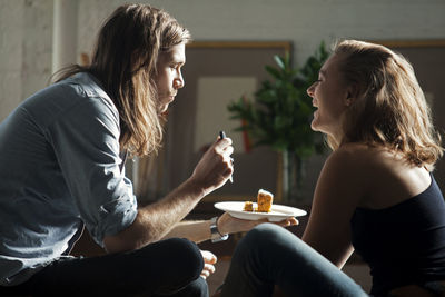 Side view of couple eating together while sitting at home