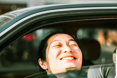 Close-up of smiling young woman in car