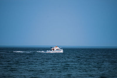 Boat sailing in sea against clear sky