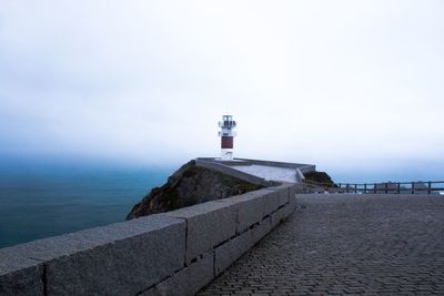 Lighthouse by sea against sky