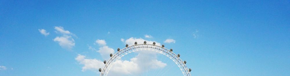 Low angle view of ferris wheel against cloudy sky