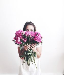 Portrait of woman holding bouquet against white background