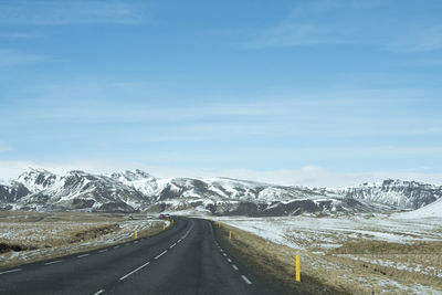 Road amidst snowcapped landscape against sky