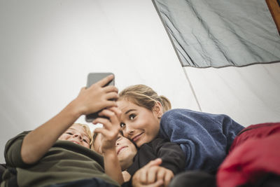 Low angle view of man using smart phone on bed at home