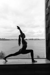 Full length of woman doing yoga at beach