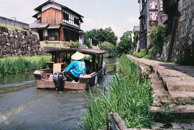 Man sitting on riverbank against sky