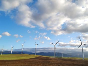 Wind turbines on field against sky