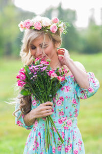 Midsection of woman holding pink flower