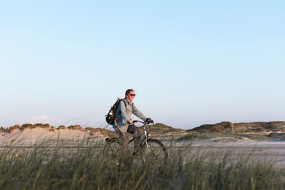 Rear view of man standing on rock against clear sky