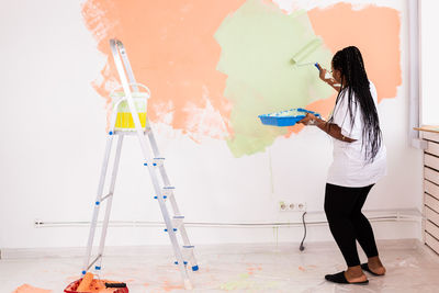 Full length of woman standing against wall