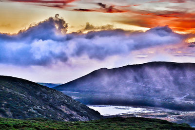 Scenic view of sea and mountains against dramatic sky